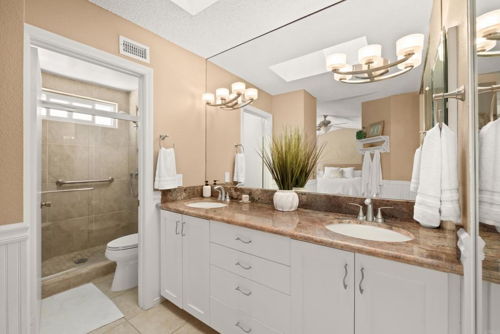 1361 Hodges Road Oceanside, CA 92056 - Photo 29 of 39 a bathroom with a granite countertop sink a toilet and a mirror