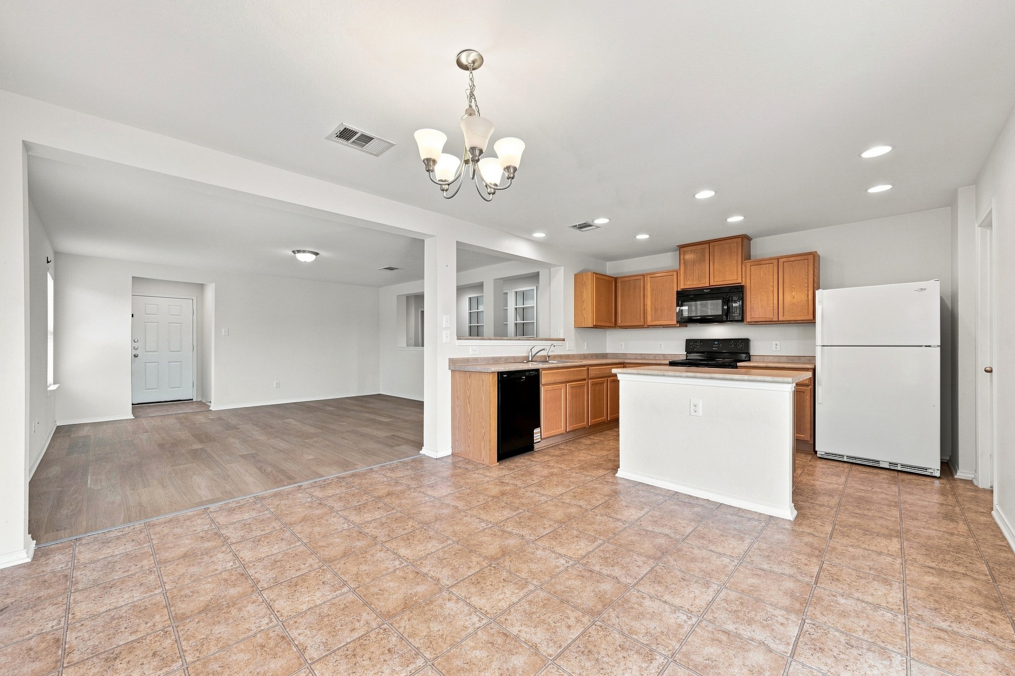 An open kitchen layout flows seamlessly into the adjoining living space over tile flooring.