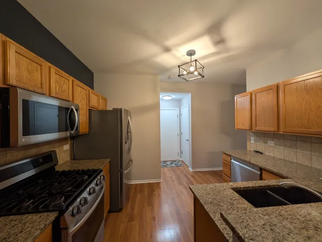a kitchen with granite countertop a sink cabinets and stainless steel appliances