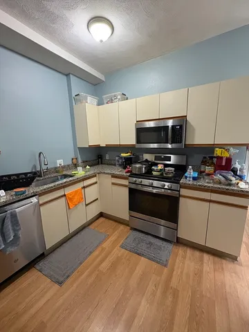 a kitchen with granite countertop a sink cabinets and stainless steel appliances