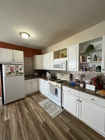a kitchen with granite countertop white cabinets and white appliances