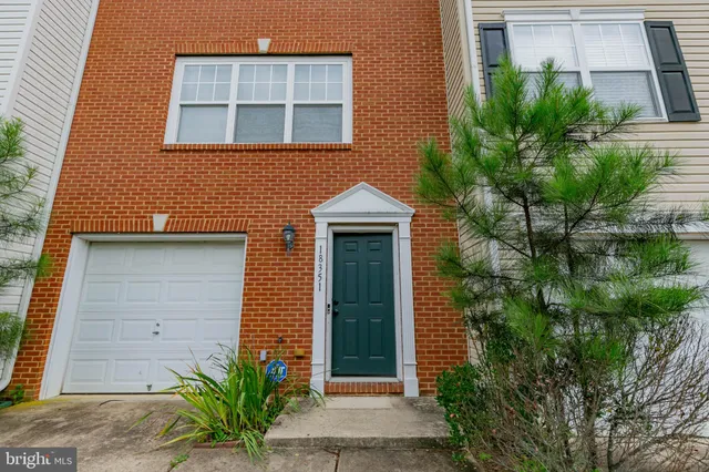 a view of a brick house with a large window and potted plants