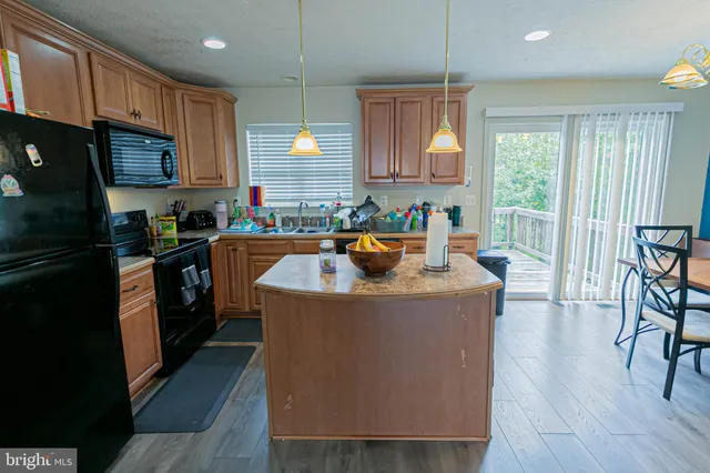 a kitchen with granite countertop a stove a sink a refrigerator and cabinets