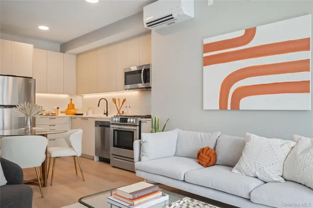 a living room with stainless steel appliances furniture and a kitchen view