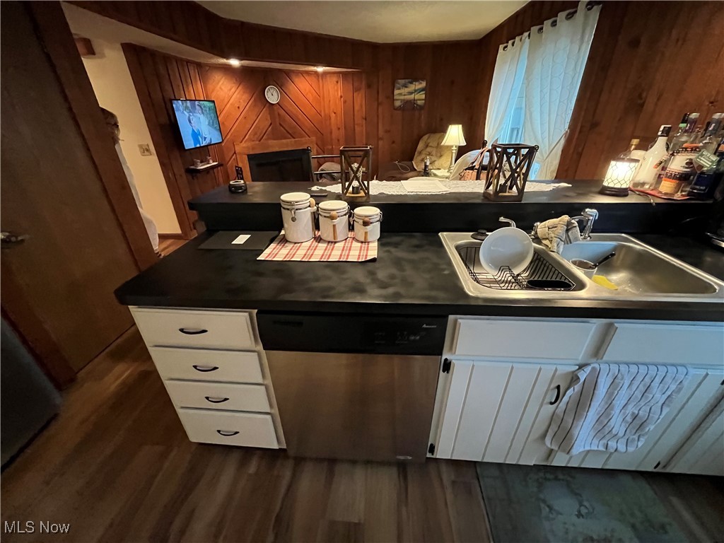 1455 Welch Road Painesville, OH 44077 - Photo 10 of 42 Bar area with white cabinetry, dark countertops, stainless steel dishwasher, wood walls, and dark wood-style flooring