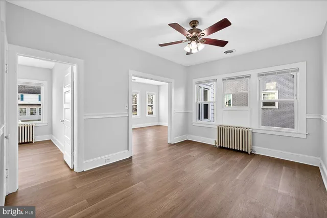 a view of a livingroom with wooden floor and a ceiling fan