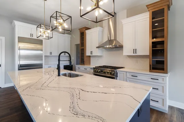 a kitchen with stainless steel appliances granite countertop a sink a stove and refrigerator