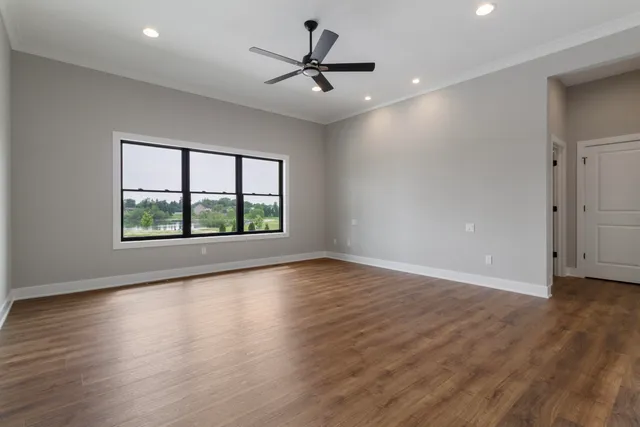 an empty room with wooden floor and windows