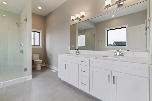 a spacious bathroom with a double vanity sink mirror and shower