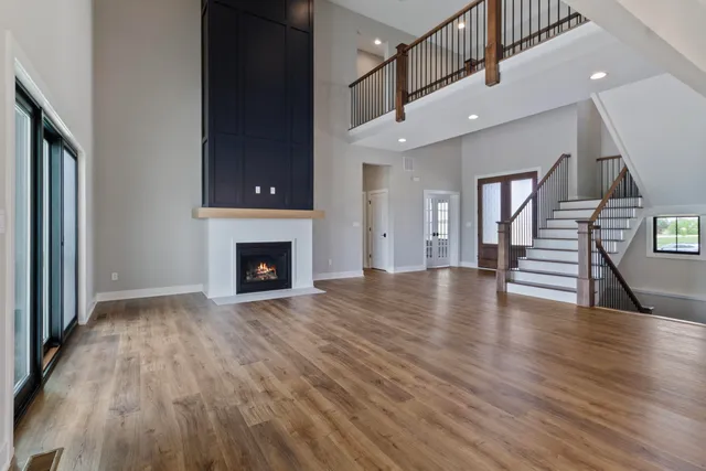 a view of an empty room with wooden floor fireplace and a window