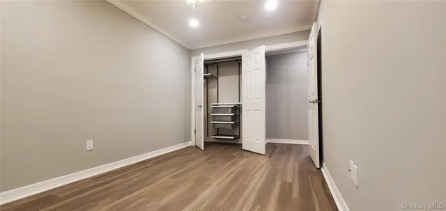a view of an empty room with wooden floor and closet