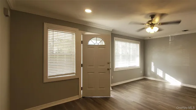 a view of an empty room with a window and wooden floor