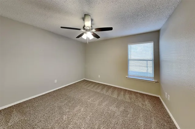 an empty room with a window and a fan