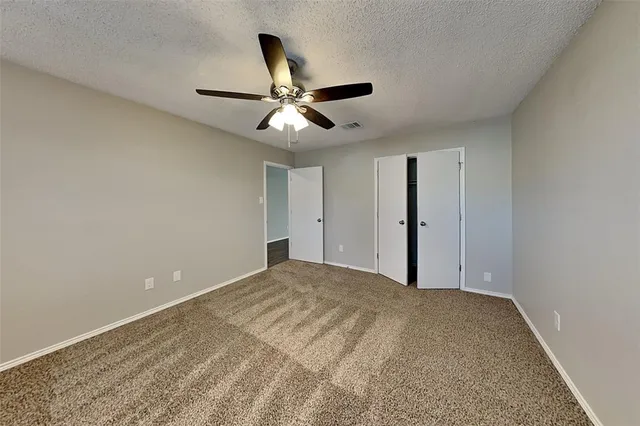a view of a big room with carpet and chandelier fan