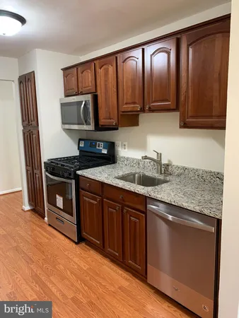a kitchen with stainless steel appliances granite countertop a stove a sink dishwasher and a microwave oven with wooden cabinets