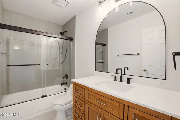 a bathroom with a sink a toilet a mirror and shower