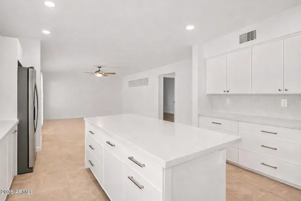 a kitchen that has a refrigerator a sink and white cabinets with wooden floor