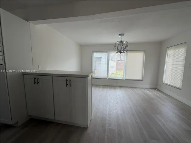 an empty room with wooden floor cabinet and windows