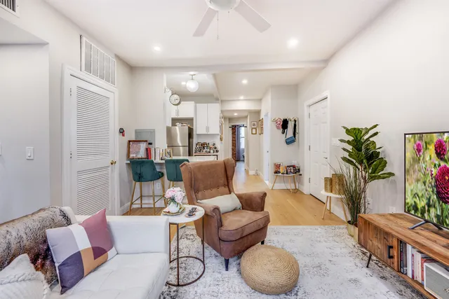 a kitchen with stainless steel appliances a stove a refrigerator a sink and white cabinets with wooden floor