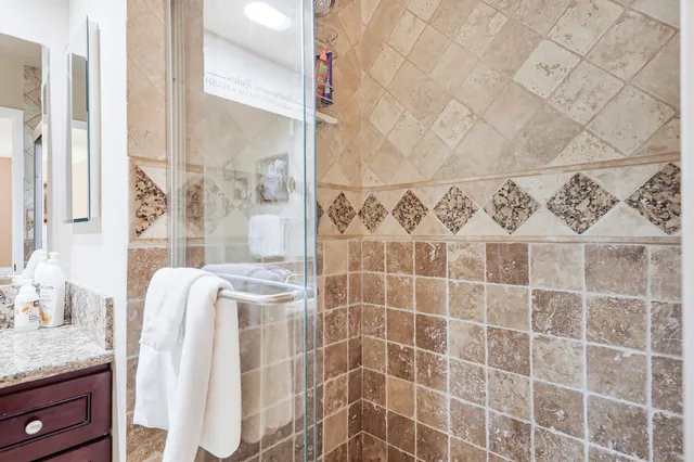a bathroom with a granite countertop shower a sink and a mirror