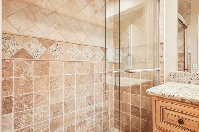 a bathroom with a granite countertop sink a shower and a mirror