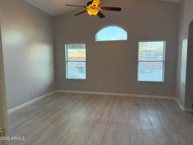 an empty room with wooden floor windows and chandelier fan