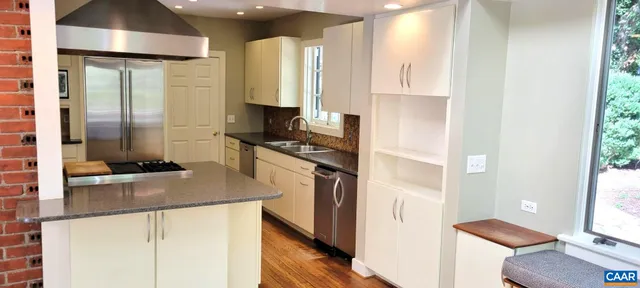 a kitchen with stainless steel appliances granite countertop a refrigerator a stove and a sink with wooden floor