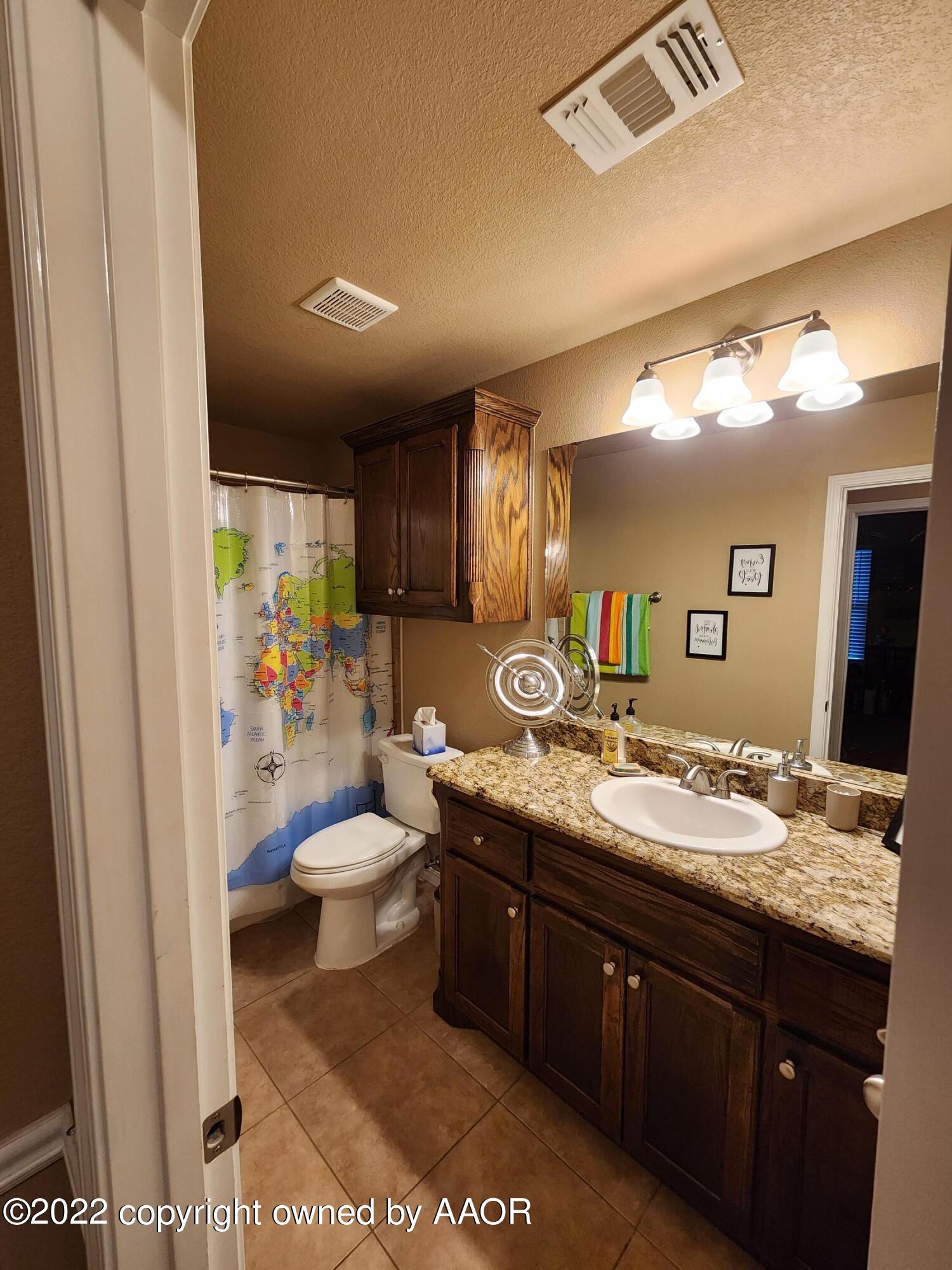 3912 Arden Road Amarillo, TX 79118 - Photo 28 of 35 a bathroom with a granite countertop sink a toilet a mirror and shower