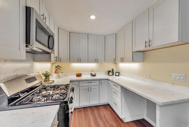 a kitchen with stainless steel appliances a sink dishwasher stove and cabinets with wooden floor