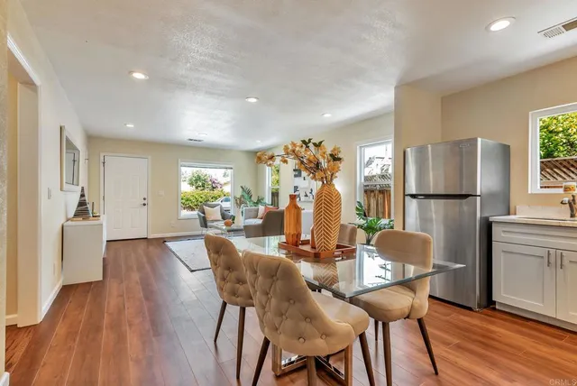 a living room with furniture a refrigerator and a dining table with wooden floor