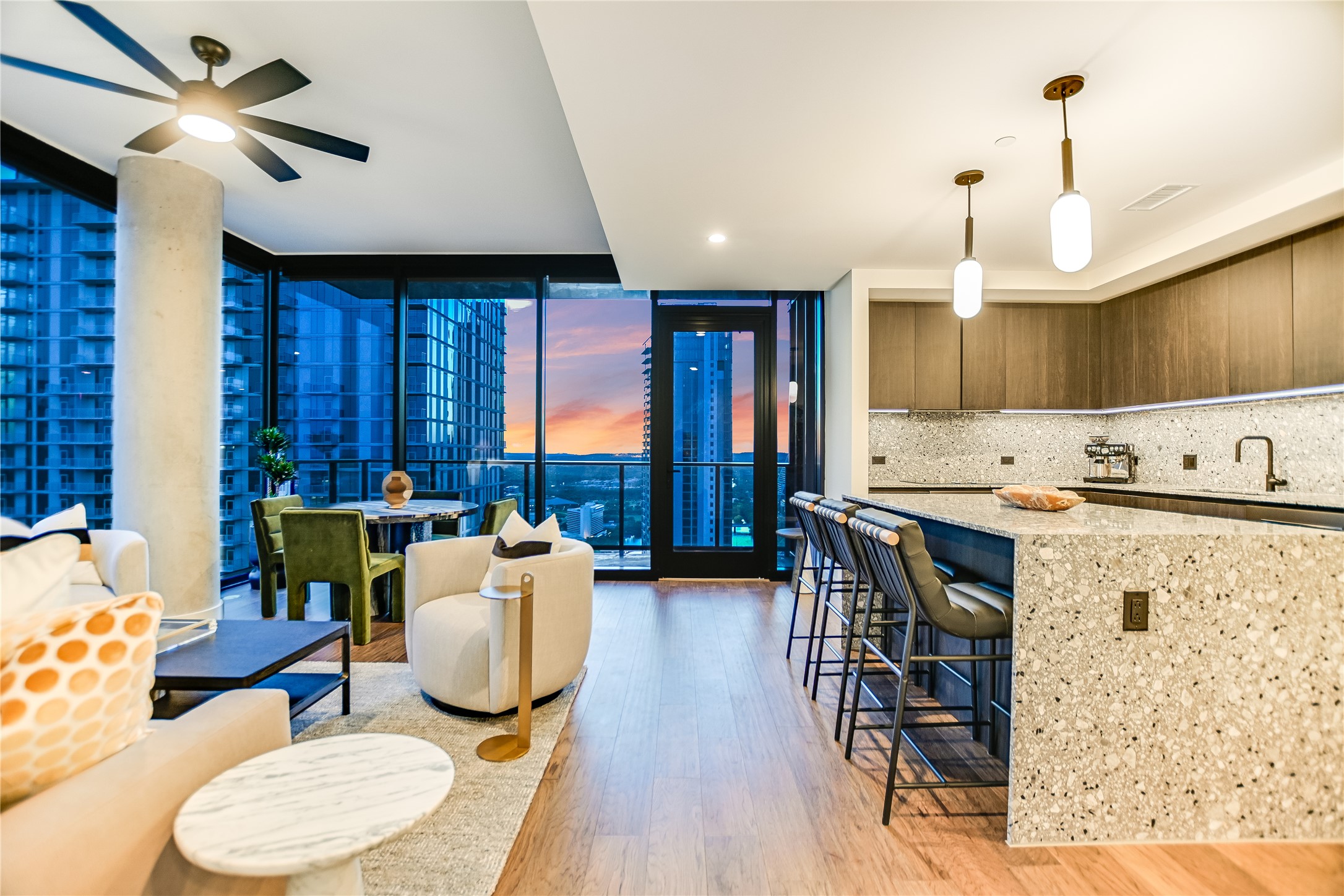 84 East Avenue, Unit 3909 Austin, TX 78701 - Photo 24 of 26 Kitchen with expansive windows, light stone counters, light wood-style flooring, hanging light fixtures, and a breakfast bar area