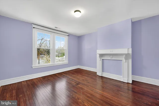 an empty room with wooden floor cabinet and windows