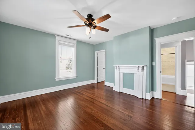 an empty room with wooden floor chandelier fan and windows