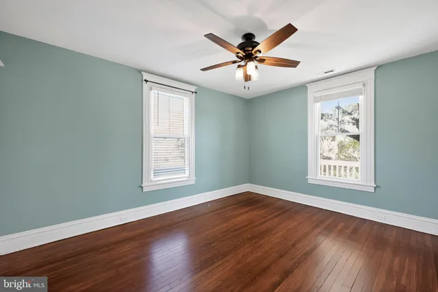 a view of a big room with wooden floor and windows