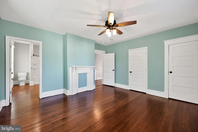 an empty room with wooden floor ceiling fan and windows