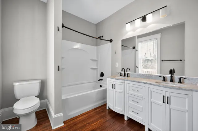 a bathroom with a granite countertop sink toilet a large mirror a bathtub and shower