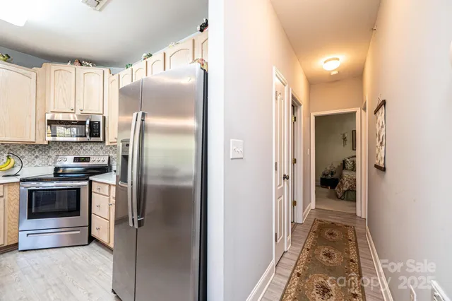 a kitchen with a refrigerator and a view of living room