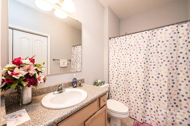 a bathroom with a granite countertop sink a toilet a mirror and shower curtain