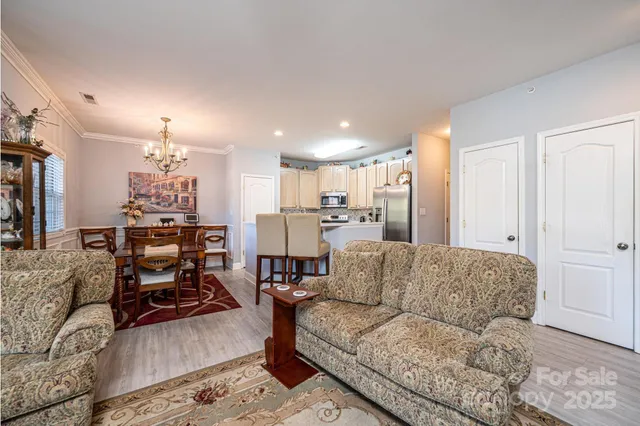 a living room with furniture kitchen view and a chandelier
