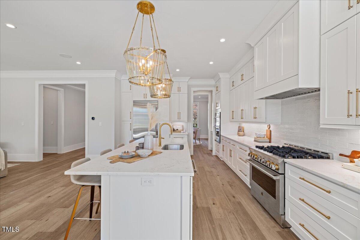 4906 Tremont Drive Raleigh, NC 27609 - Photo 16 of 71 a kitchen with stainless steel appliances a stove a sink dishwasher and white cabinets with wooden floor