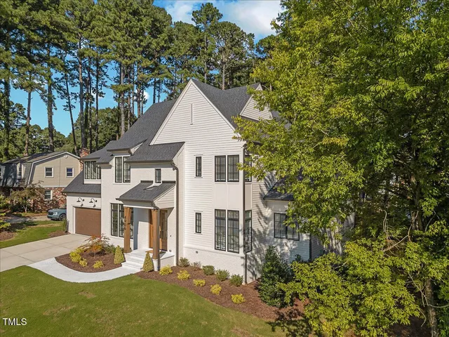 a view of a white house with a small yard and plants