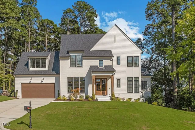 a view of a white house with a big yard and large trees