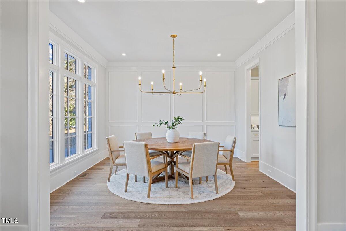 4906 Tremont Drive Raleigh, NC 27609 - Photo 7 of 71 a dining room with wooden floor a chandelier a wooden table and chairs