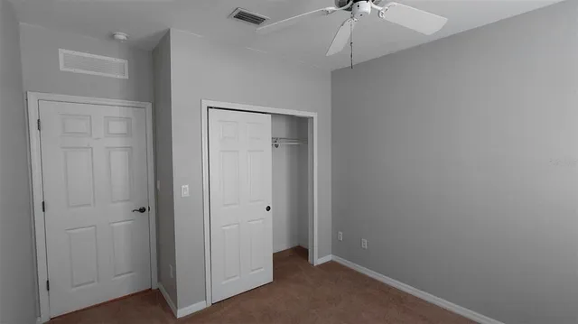 an empty room with a ceiling fan and carpet