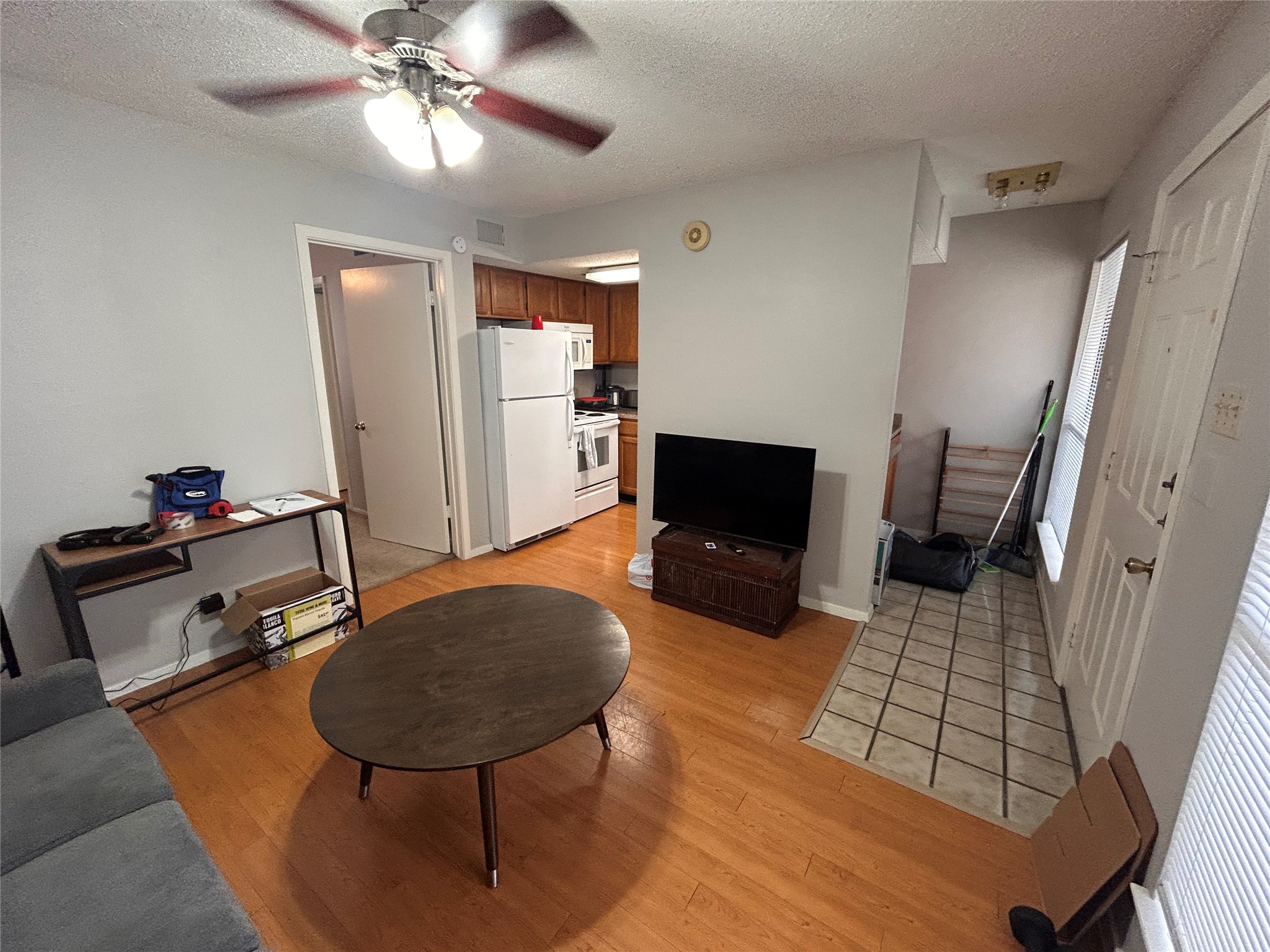 Living area featuring a textured ceiling, a ceiling fan, and light wood finished floors