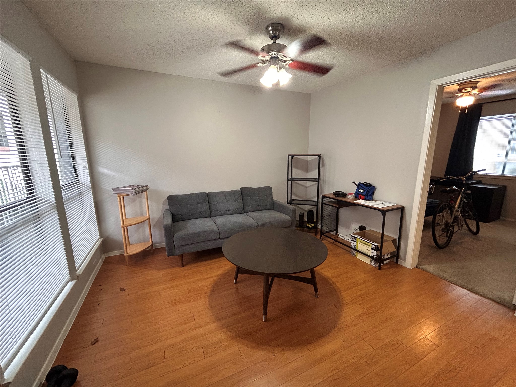 3115 Helms Street, Unit 109 Austin, TX 78705 - Photo 2 of 9 Living area featuring ceiling fan, hardwood / wood-style flooring, and a textured ceiling