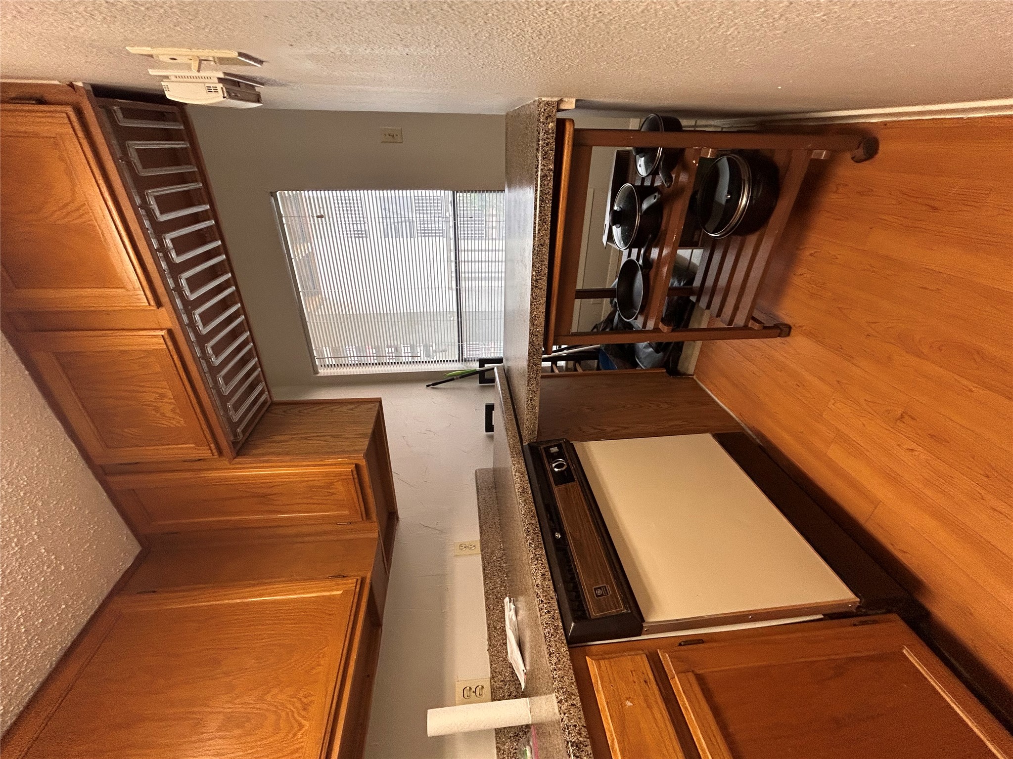 3115 Helms Street, Unit 109 Austin, TX 78705 - Photo 5 of 9 Kitchen featuring wood finish cabinets, light wood-style floors, a textured ceiling, white dishwasher, and a textured wall