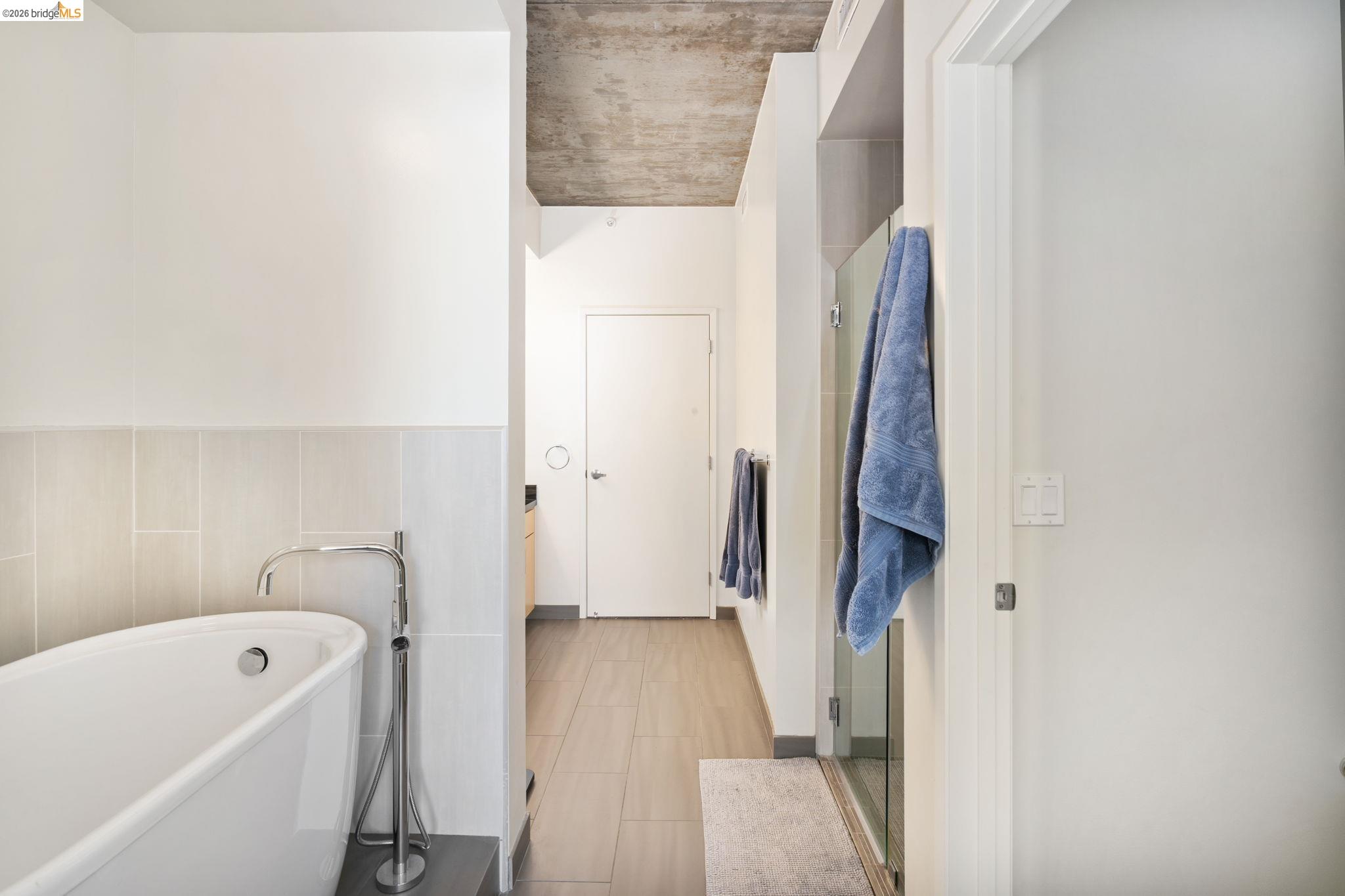 311 2nd Street, Unit 511 Oakland, CA 94607 - Photo 28 of 44 Bathroom featuring a freestanding bath, a stall shower, and tile walls