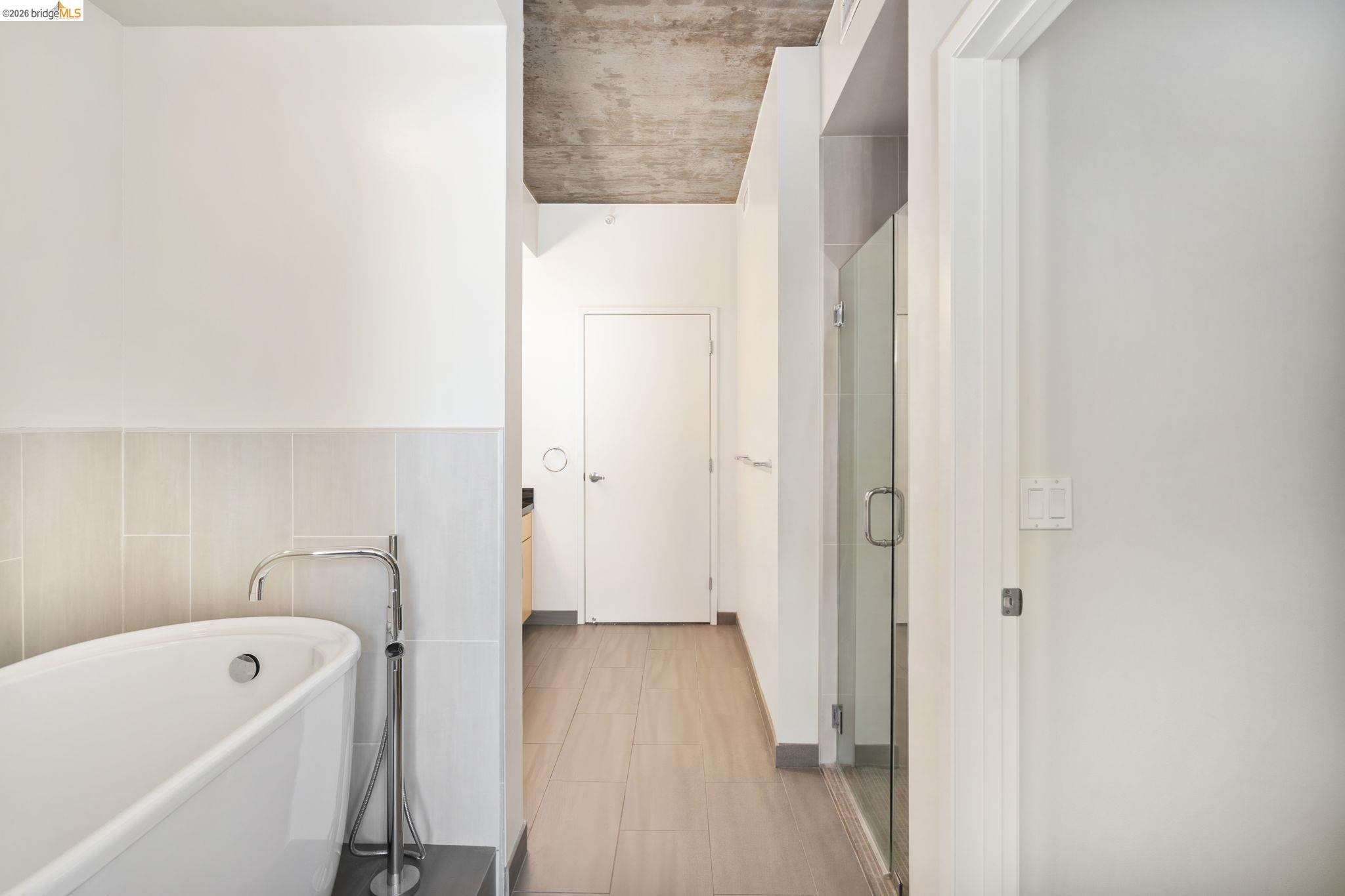 311 2nd Street, Unit 511 Oakland, CA 94607 - Photo 29 of 44 Full bath featuring a freestanding bath, a shower stall, and tile walls