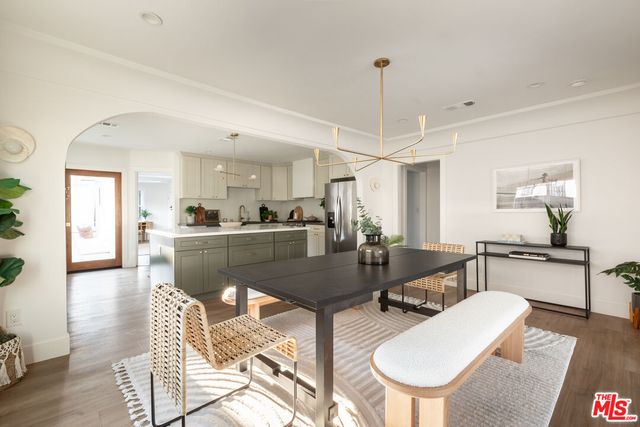 a living room with couches chairs and kitchen view with wooden floor